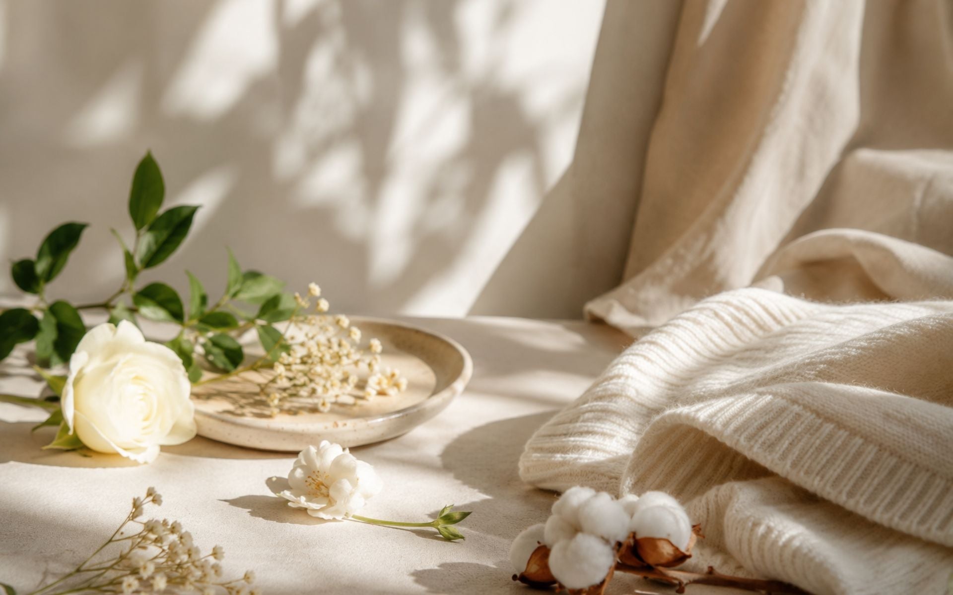 Composition de fleurs blanches, coton et textile doux évoquant un univers olfactif léger et des parfums aux senteurs délicates.
